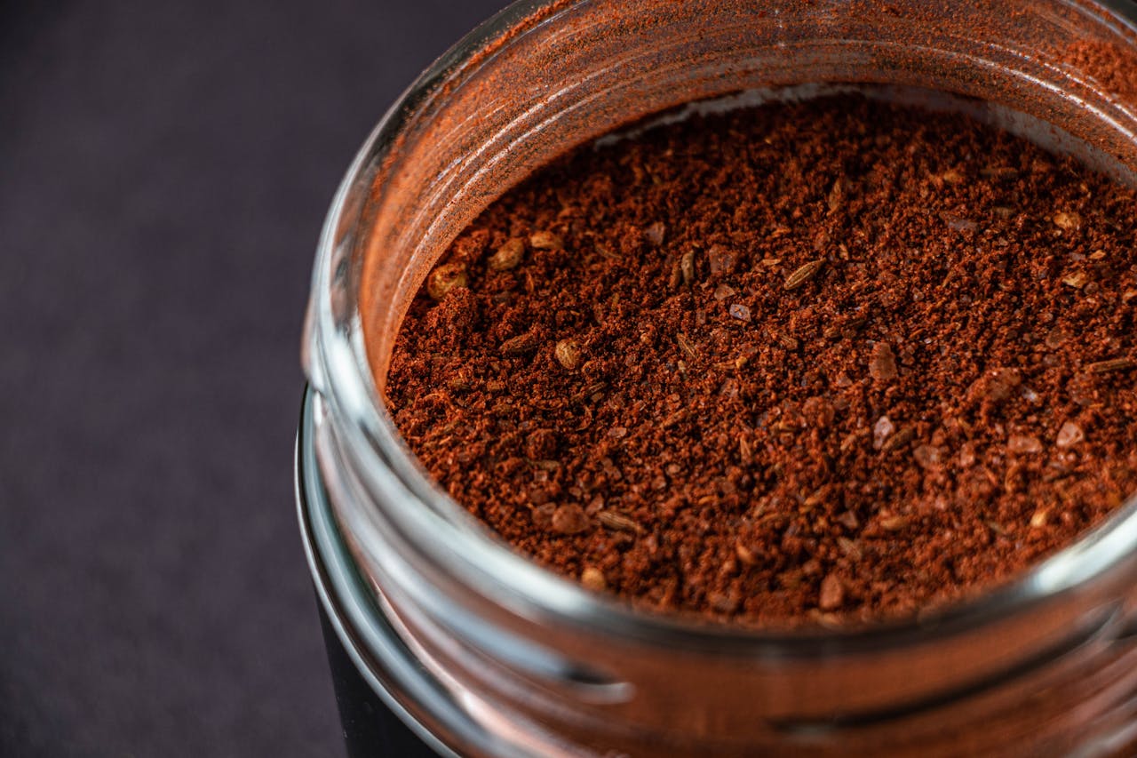 A detailed close-up of spicy ground chili powder in a glass jar, showcasing its rich texture.